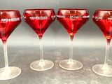 four red wine glasses are lined up on a table