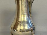 une cafetière ancienne en argent posée sur un support, sur fond blanc