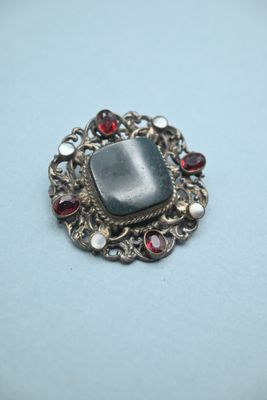 a close up of a silver broochle with garnets on it