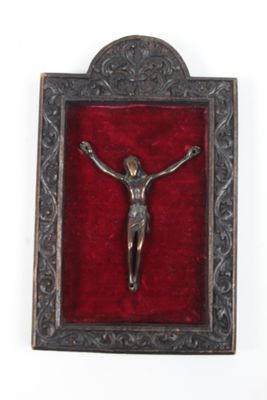 crucifix en métal argenté posé sur du velours rouge, dans un cadre ouvragé