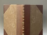 un vieux livre à la couverture marron posé sur une table blanche