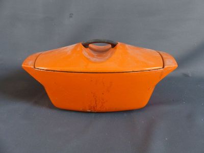un plat à gratin orange avec un couvercle posé sur une table