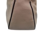 the back view of a beige purse with a black handle