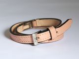 ceinture en cuir rose avec boucle argentée sur fond blanc
