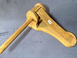 une pince en bois munie d'un manche en bois, posée sur une surface grise