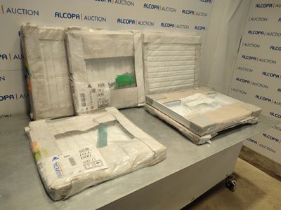 Plusieurs cartons contenant des matelas sont empilés sur une table devant un mur.