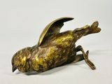 sculpture en bronze représentant un oiseau sur une surface blanche, avec un fond blanc