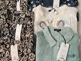 several shirts are lined up on a shelf with tags on them
