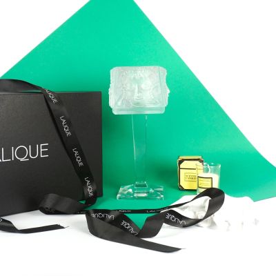 an image of a bottle of perfume next to a box and ribbon