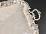 an ornate silver tray with a handle on a black surface
