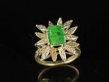 an emerald and diamond ring on a black surface