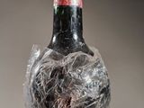 a bottle of wine wrapped in plastic on a table