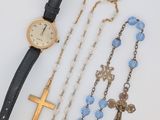 une montre, des bracelets et un chapelet posés sur une table