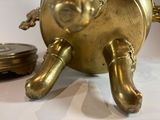 a small brass object on a table next to a coin