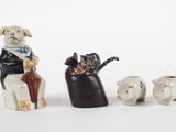 three figurines of dogs and a cat sitting on a chair