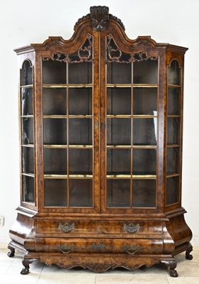 une vieille vitrine en bois avec des portes vitrées, posée sur un sol carrelé