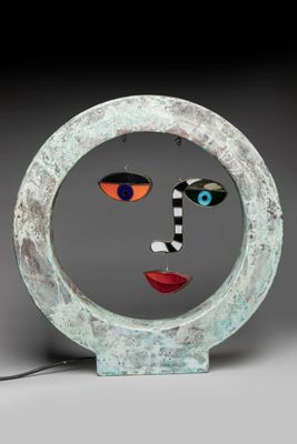 sculpture of a woman ' s face in a circle with a black background
