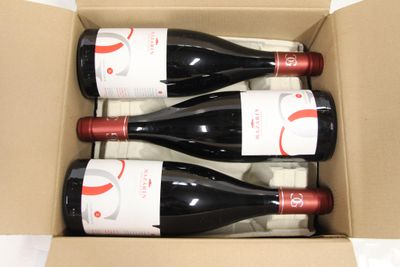 three bottles of red wine in a cardboard box on a table