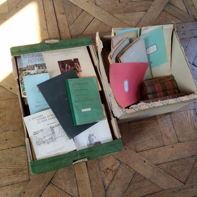 two open boxes with books and papers in them on the floor
