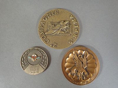 two gold coins and a silver coin on a white surface