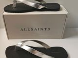 the box is white and has a pair of silver sandals on it