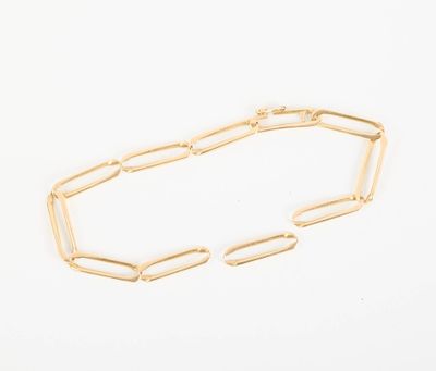 gros plan d'un bracelet en chaîne en or sur une surface blanche