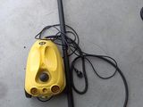 a yellow pressurer on the ground next to a black hose