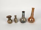 quatre vases en verre de couleurs différentes posés les uns à côté des autres sur une surface blanche