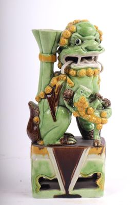 une statue représentant un dragon vert tenant un vase vert