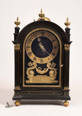 une horloge noire et or posée sur une surface blanche