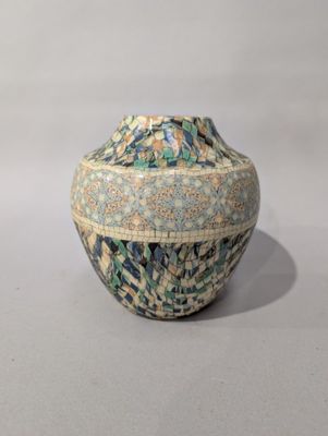 a blue and green vase sitting on a white surface