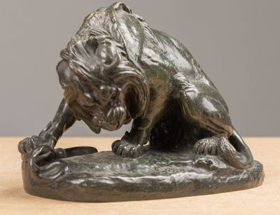 bronze statue of a lion on a rock on a table