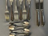 a lot of forks and spoons laid out on a table
