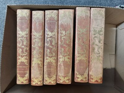 six livres dans une boîte en carton posée sur une surface bleue