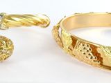 two gold rings and a bracelet are sitting on a white surface