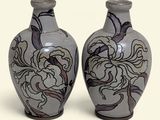 two vases that are sitting side by side on a white surface