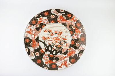 une assiette orange et noire ornée de fleurs sur un fond blanc
