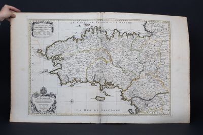 an old map of the kingdom of england with a person holding it