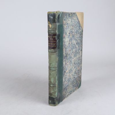 un vieux livre posé sur une table blanche à côté d'un mur blanc