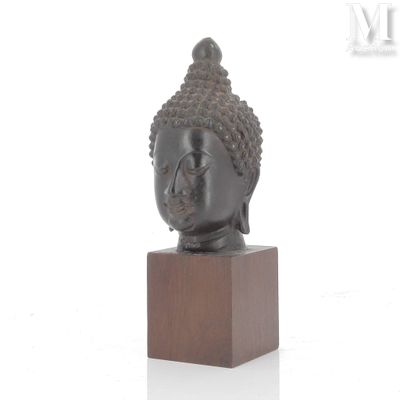 statue représentant une tête de Bouddha posée sur un socle en bois, sur fond blanc