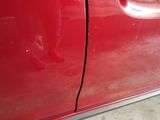 a close up of a red car with a broken door handle