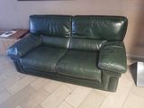 a green leather couch in a living room with a picture on the wall