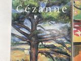 three books on a table with a painting of a tree in front of them