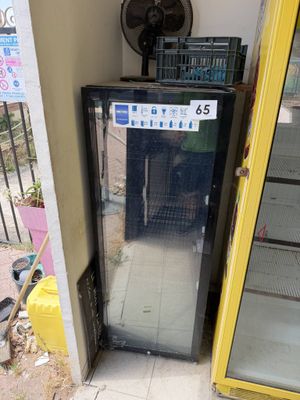 a refrigerator that is outside of a building with a fan in the background