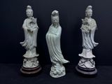 trois statues blanches représentant des femmes asiatiques, posées sur des socles, sur fond noir