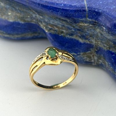 an image of a close up of a ring with a green stone in the background
