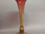 un vase en verre rouge posé sur une table blanche