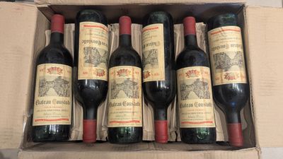 six bottles of red wine in a cardboard box on a table
