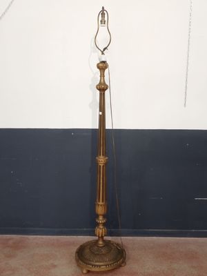 an antique brass floor lamp with a glass shade on top of it