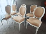 quatre chaises blanches aux assises rembourrées beiges dans une pièce